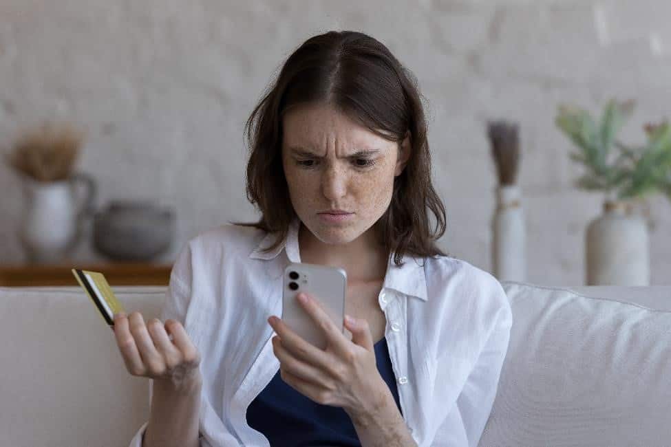 Women looking at cell phone with a credit card in her hand