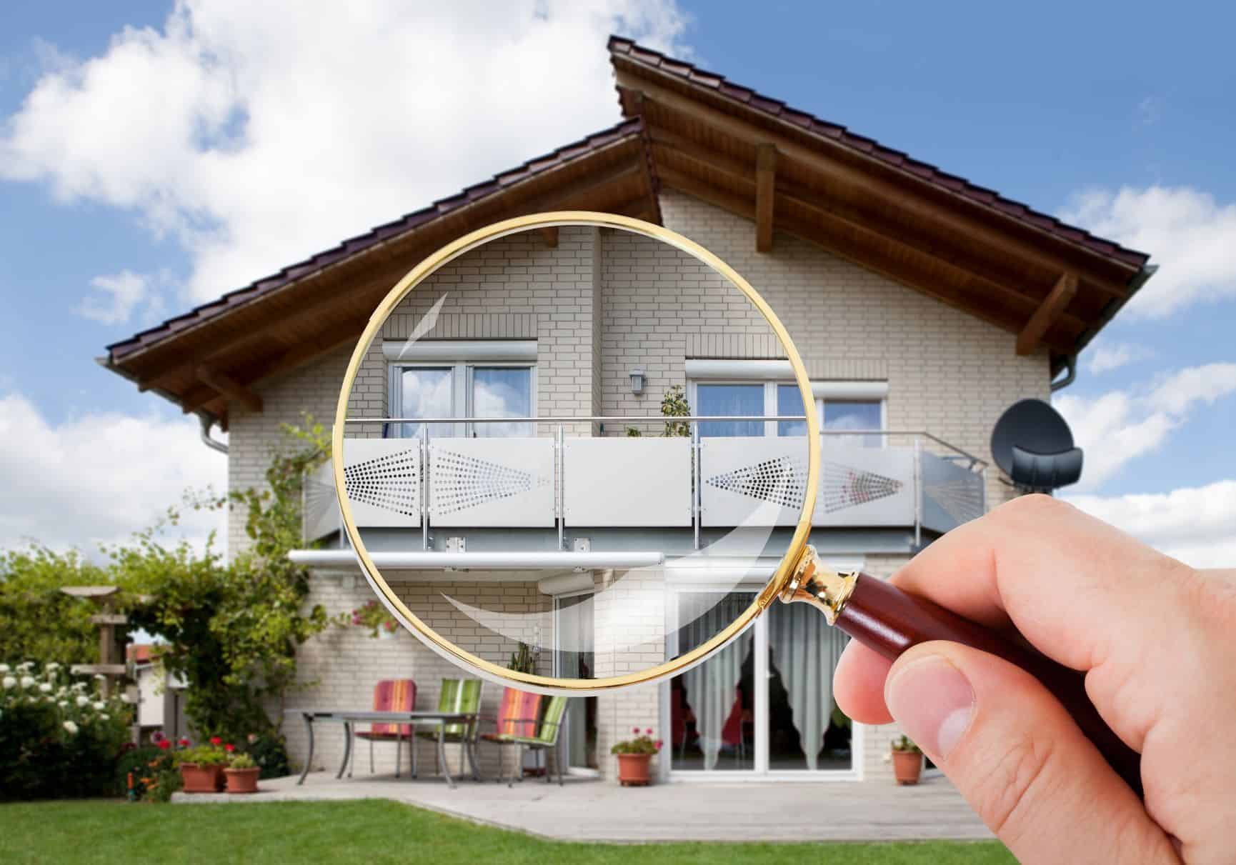 Person holding magnifying glass over a house