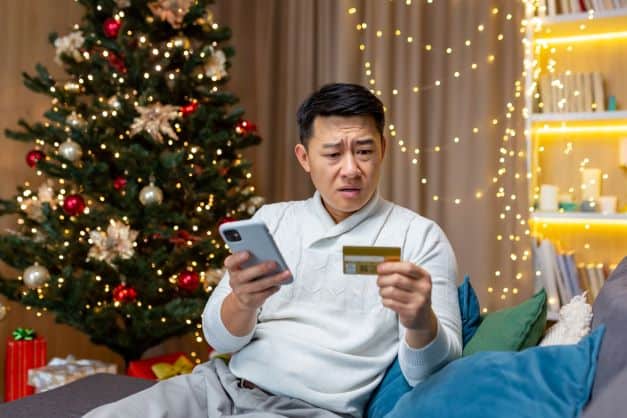 Man holding cell phone and looking at credit card