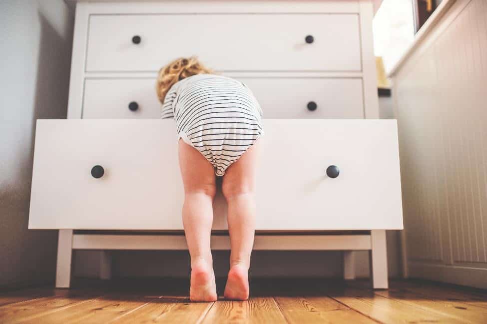 Child leaning into dresser drawer