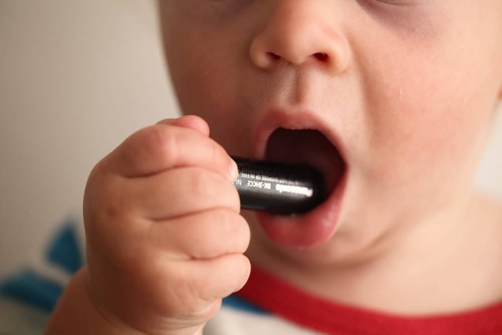 Toddler putting a battery in their mouth