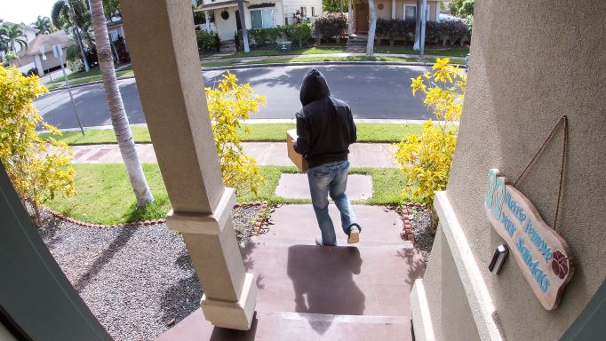 Porch pirate leaving house holding package