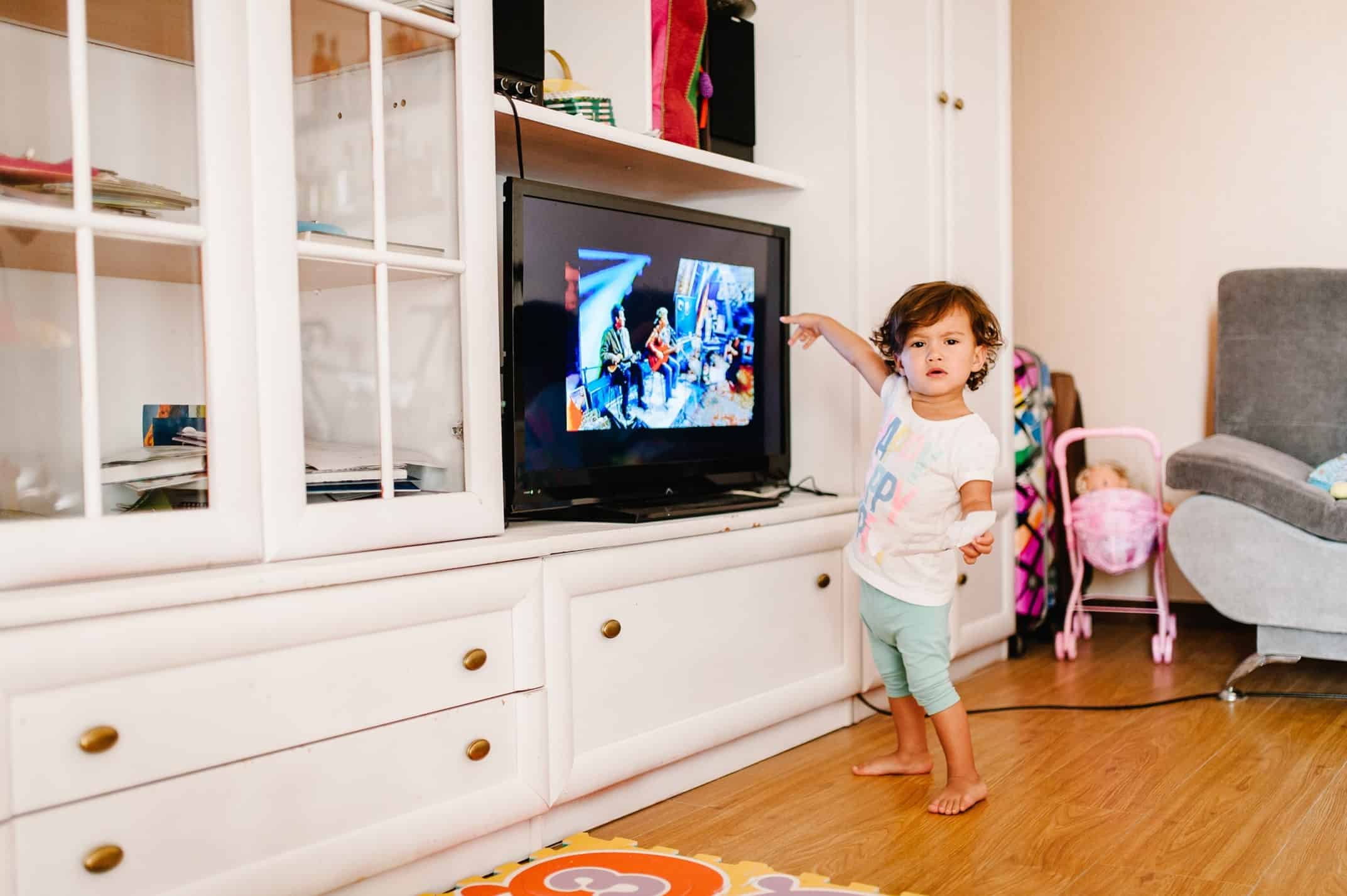A toddler touching a TV