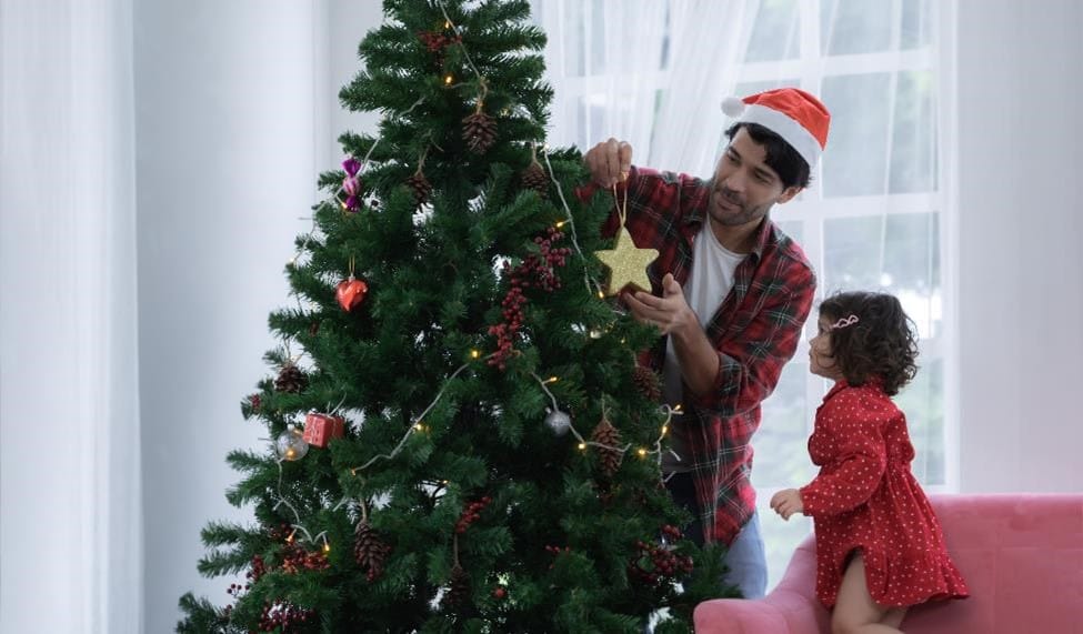 A father and child setting up a Christmas tree