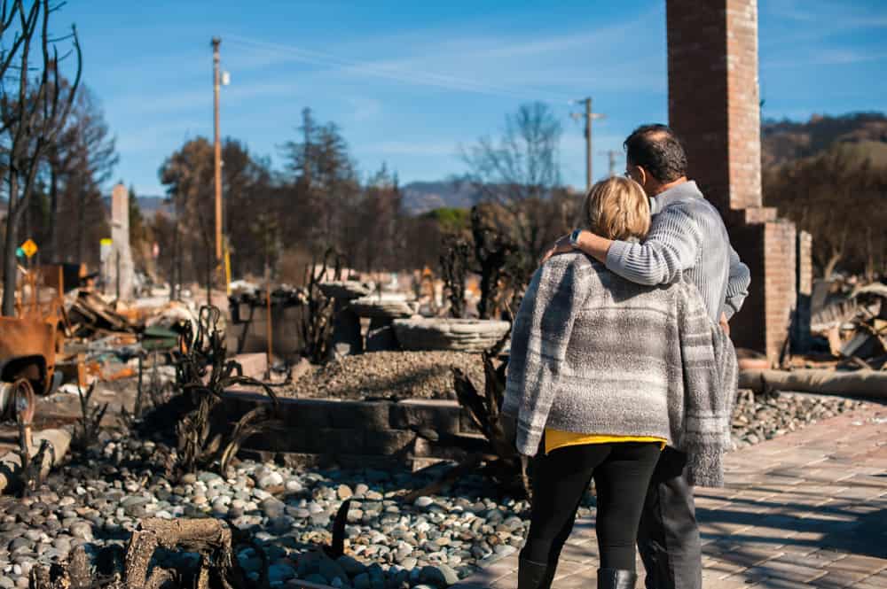 A man and woman looking at a collapsed home