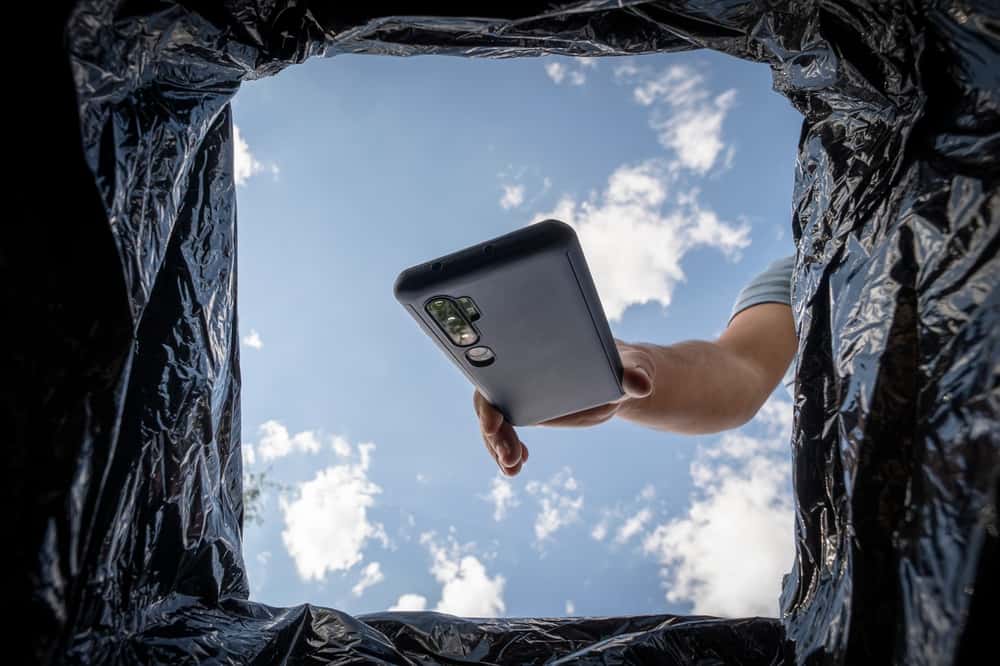 Person throwing a phone in a garbage bin