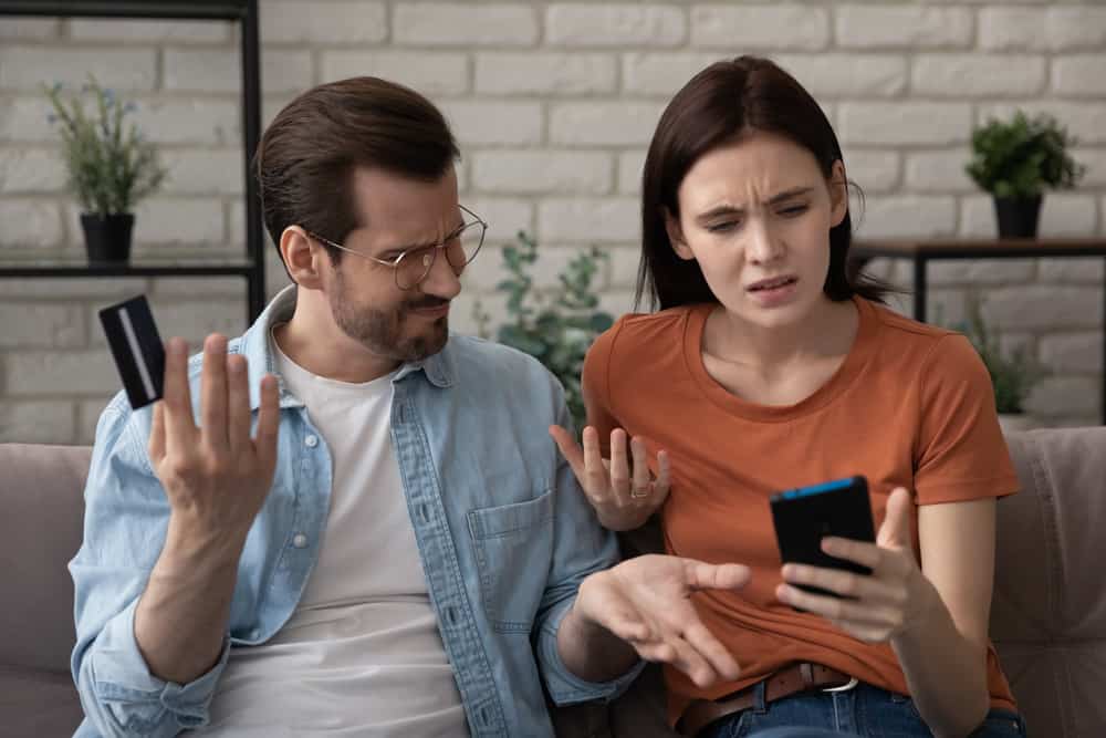 An annoyed couple looking at bills on a phone